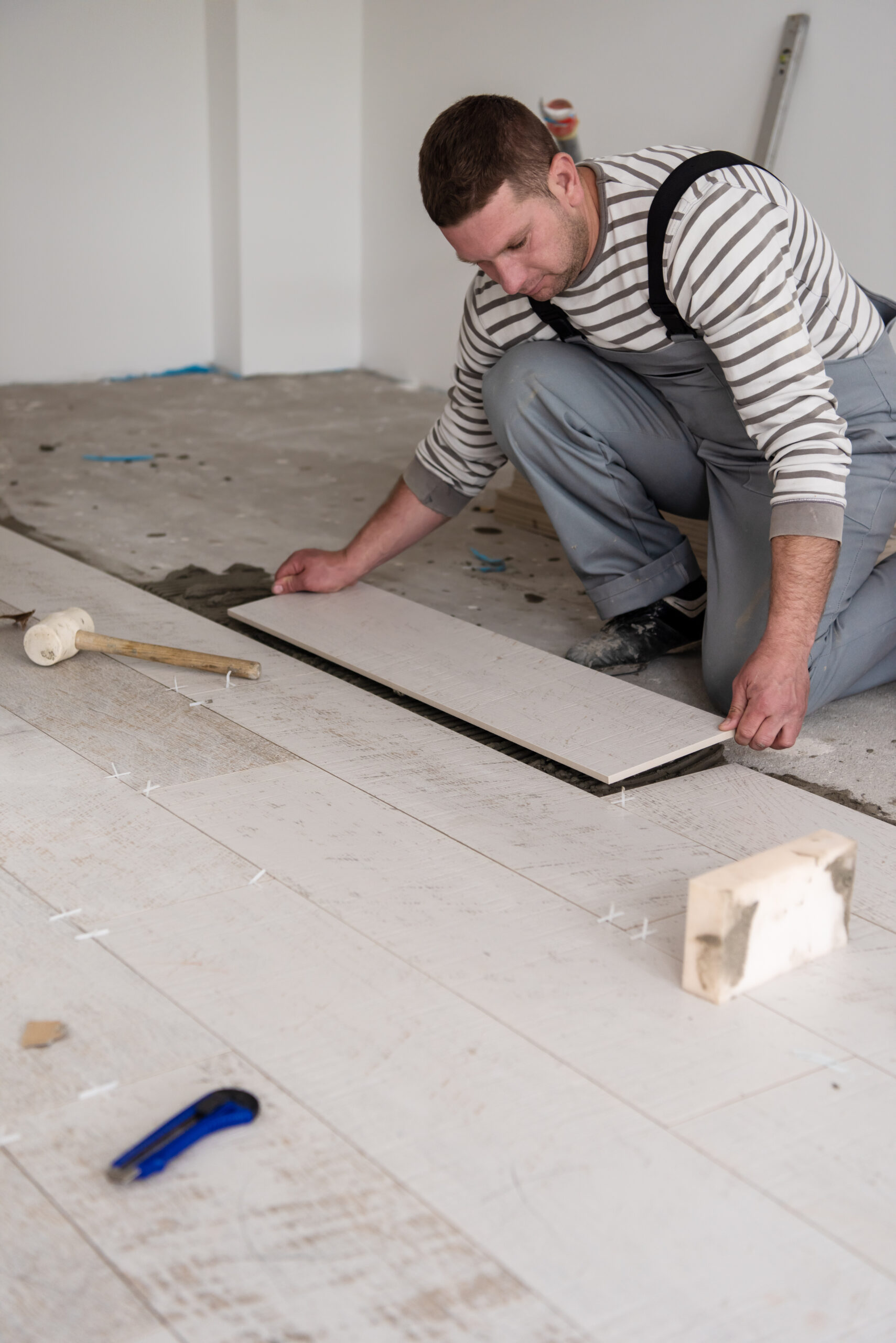 skilled worker installing the ceramic wood effect tiles on the floor Worker making laminate flooring on the construction site of the new apartment